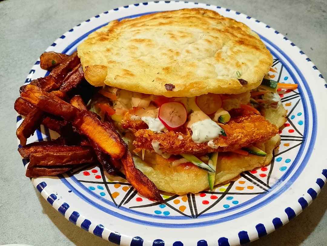 Sandwich Le M'ze – Pain au lait de coco, viande kebab ou version végétarienne, crudités fraîches, oignons caramélisés, fêta, sauce blanche maison, spécialité comorienne